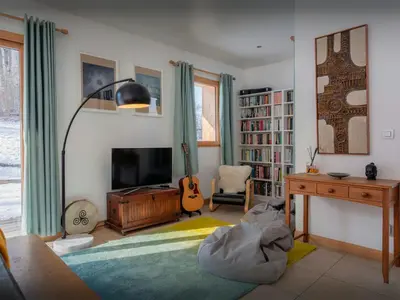 a living room with a television and a desk and a guitar at Chalet Nordchamp - OVO Network in Samoëns