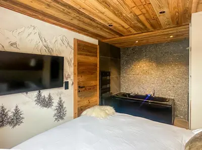 a bedroom with a bed with a television and a sink at My Way Megeve village 5 rues parking in Megève