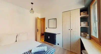 a bedroom with a white bed and a wooden cabinet at Bright, warm 2BR 2min to gondola, private garden in Chamonix-Mont-Blanc