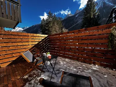 a wooden fence with a table and a chair on a patio at Jonquille 2 - Centre - Terrasse Privee - Vues in Chamonix-Mont-Blanc