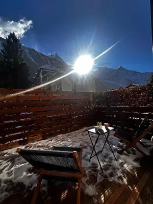 a sun shining on a deck with a table and chairs at Jonquille 2 - Centre - Terrasse Privee - Vues in Chamonix-Mont-Blanc