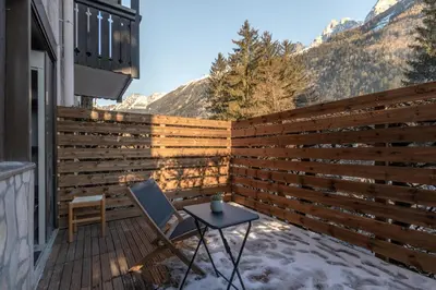 a wooden fence on a patio with a chair and a table at Jonquille 2 - Centre - Terrasse Privee - Vues in Chamonix-Mont-Blanc