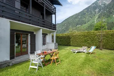 a patio with chairs and a table on the grass at Cozy big Chalet with Spectacular Mont-Blanc View in Chamonix-Mont-Blanc