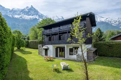 a house with a garden and mountains in the background at Cozy big Chalet with Spectacular Mont-Blanc View in Chamonix-Mont-Blanc