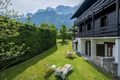 a backyard with chairs and tables and a building at Cozy big Chalet with Spectacular Mont-Blanc View in Chamonix-Mont-Blanc
