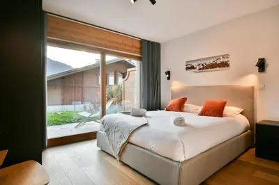 a bedroom with a large bed and a large window at Les Carlines 01 in Samoëns