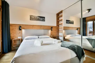 two beds in a hotel room with mirrors at Les Carlines 01 in Samoëns