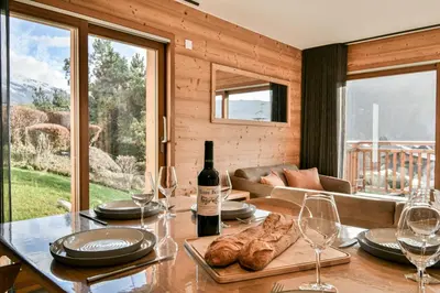 a table with a bottle of wine and some wine glasses at Les Carlines 01 in Samoëns