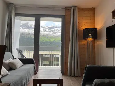 a living room with a couch and a large window at appartement petite ourse flaine 2chambres avec wifi in Flaine