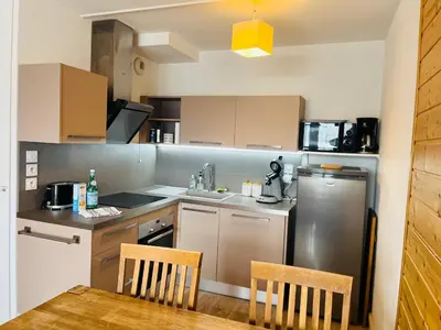 a kitchen with a refrigerator and a table and chairs at appartement petite ourse flaine 2chambres avec wifi in Flaine