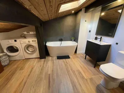 a bathroom with a tub and a sink and a washing machine at Duplex départ randonnée Megeve in Demi-Quartier