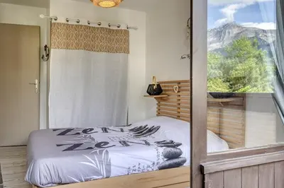 a bedroom with a bed with a view of a mountain at Appartement Cosy - 1 à 2 chambres proche thermes et ski in Saint-Gervais-les-Bains