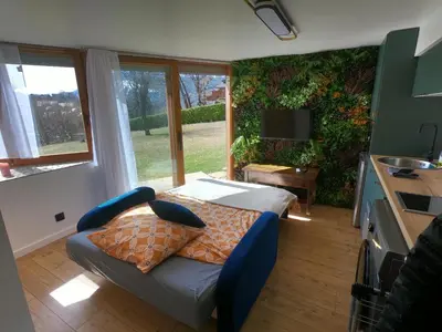 a room with a couch and a kitchen with a window at Jungle room au centre des Carroz in Les Carroz d'Araches