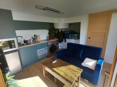 a living room with a blue couch and a table at Jungle room au centre des Carroz in Les Carroz d'Araches