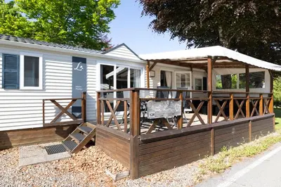 a house with a large deck with a tent at Mobil-home 5 pers - camping Samoens in Samoëns