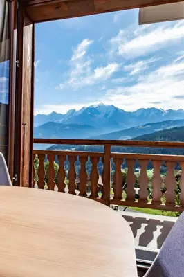 a table on a balcony with a view of mountains at Appartement de charme au pied des pistes de Cordon in Cordon