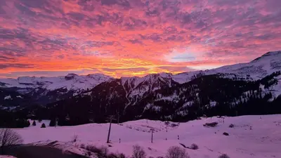 a sunset over a snow covered mountain range with the sky at Studio Vue Montagne, Skis aux pieds, Garage inclus in Samoëns