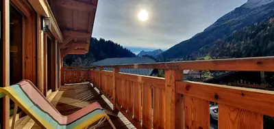 a balcony with a chair and a view of the mountains at Chalet des Ours - 2 appartements 4 étoiles premium - 5 ou 6 personnes in Les Contamines-Montjoie