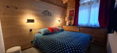 a bedroom with a bed with a wooden wall at Chalet des Ours - 2 appartements 4 étoiles premium - 5 ou 6 personnes in Les Contamines-Montjoie