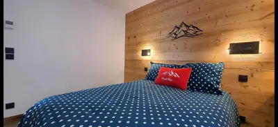 a bedroom with a blue and white bed with a wooden wall at Chalet des Ours - 2 appartements 4 étoiles premium - 5 ou 6 personnes in Les Contamines-Montjoie