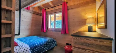 a bedroom with a bed and a window with pink curtains at Chalet des Ours - 2 appartements 4 étoiles premium - 5 ou 6 personnes in Les Contamines-Montjoie