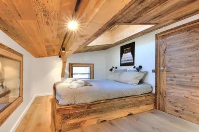 a bedroom with a bed and a wooden door at SANTA MARIA MEGEVE proche village in Megève