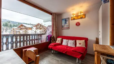 a living room with a red couch and a large window at Les Eterlous N35 - 2P4 in Morillon