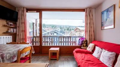 a living room with a red couch and a large window at Les Eterlous N35 - 2P4 in Morillon