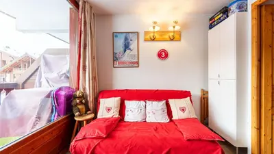 a red bed with pillows in a room at Les Eterlous N35 - 2P4 in Morillon