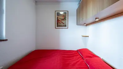 a red bed in a corner of a room at Les Eterlous N35 - 2P4 in Morillon