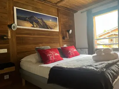 a bedroom with a bed with red pillows and a window at CHAMONIX Résidence La Cordée avec Piscine et Spa - Appartement 126 in Chamonix-Mont-Blanc