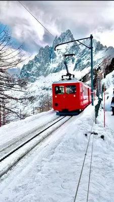 a red train on the tracks in the snow at CHAMONIX Résidence La Cordée avec Piscine et Spa - Appartement 126 in Chamonix-Mont-Blanc