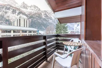 a balcony with a table and chairs and mountains at Apartment In Downtown Chamonix in Chamonix-Mont-Blanc