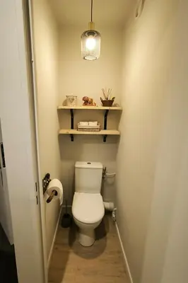 a bathroom with a toilet with a shelf above it at Appartement vue imprenable montagne in Samoëns