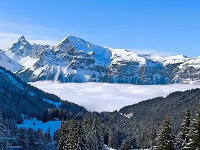 a snow covered mountain range with a layer of clouds at Appartement vue imprenable montagne in Samoëns