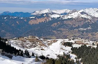 a snow covered mountain with a resort in the distance at Appartement vue imprenable montagne in Samoëns