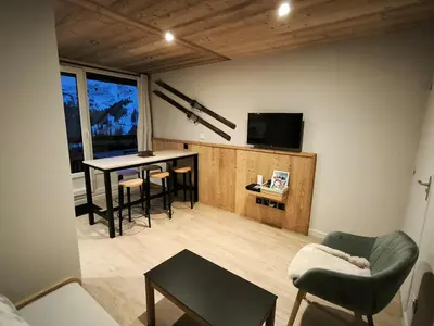 a living room with a table and a tv at Appartement vue imprenable montagne in Samoëns
