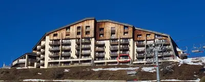 a large building with cars parked in front of it at Appartement vue imprenable montagne in Samoëns
