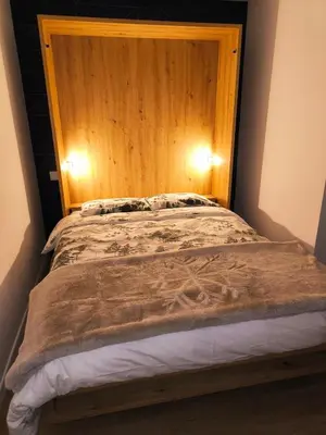 a bed with a wooden headboard in a room at Appartement vue imprenable montagne in Samoëns