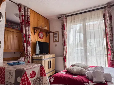 a bedroom with a bed and a tv and a window at Charmant Studio Avec Terrasse By TerraAlpina in Saint-Gervais-les-Bains