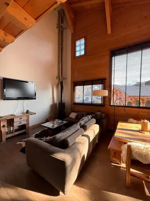 a living room with a couch and a tv at Appartement duplex megeve in Megève
