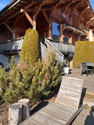 a wooden bench in front of a log cabin at Appartement duplex megeve in Megève