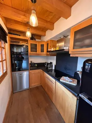 a kitchen with wooden cabinets and black counter tops at Appartement duplex megeve in Megève