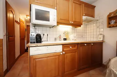 a kitchen with wooden cabinets and a microwave at Résidence Les Hauts De Chavants - Hauts de chavants Albert 1er n°3 MAE-2651 in Les Houches