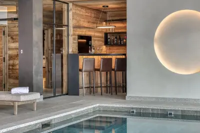 a lobby with a pool and a bar with stools at Chalet Ascension in Combloux