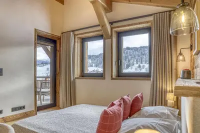 a bedroom with a bed and windows with a view at Chalet Alpes in Combloux