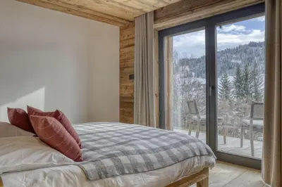a bedroom with a bed and a large window at Chalet Alpestre in Combloux