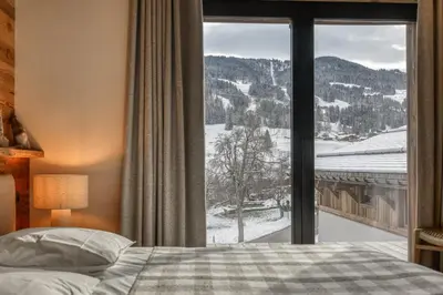 a bedroom with a bed and a large window at Chalet Alpestre in Combloux