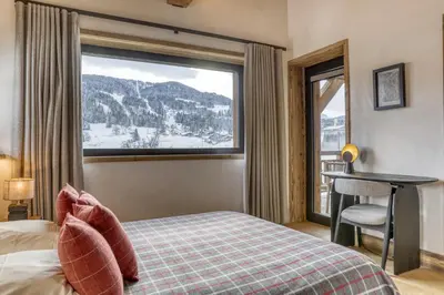 a bedroom with a bed and a large window at Chalet Alpestre in Combloux