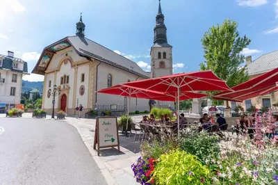 a group of people sitting at tables in front of a church at Studio Le Flocon à Saint-Gervais-les-Bains in Saint-Gervais-les-Bains